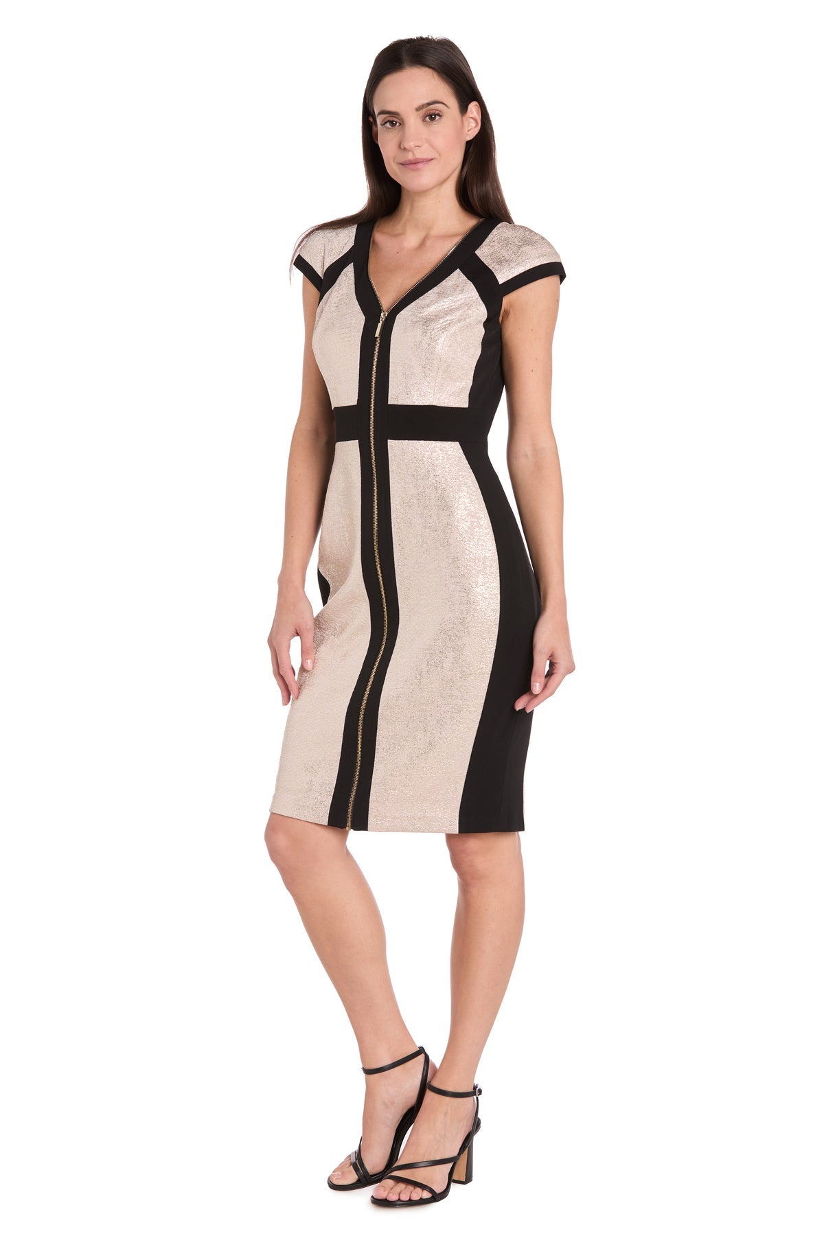 A woman models the R&M Richards 4272 Short Champagne Party Dress, a knee-length, short-sleeve semi-formal style with gold metallic panels and black trim, paired stylishly with black heeled sandals against a white background.
